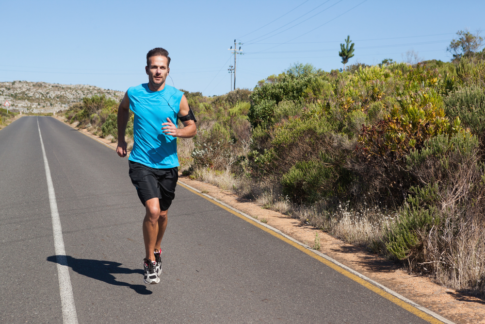 Athletic man jogging on open road on a sunny day