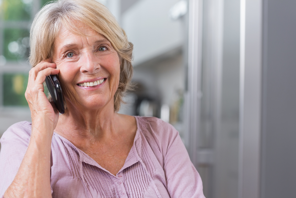 Happy mature woman calling in the kitchen